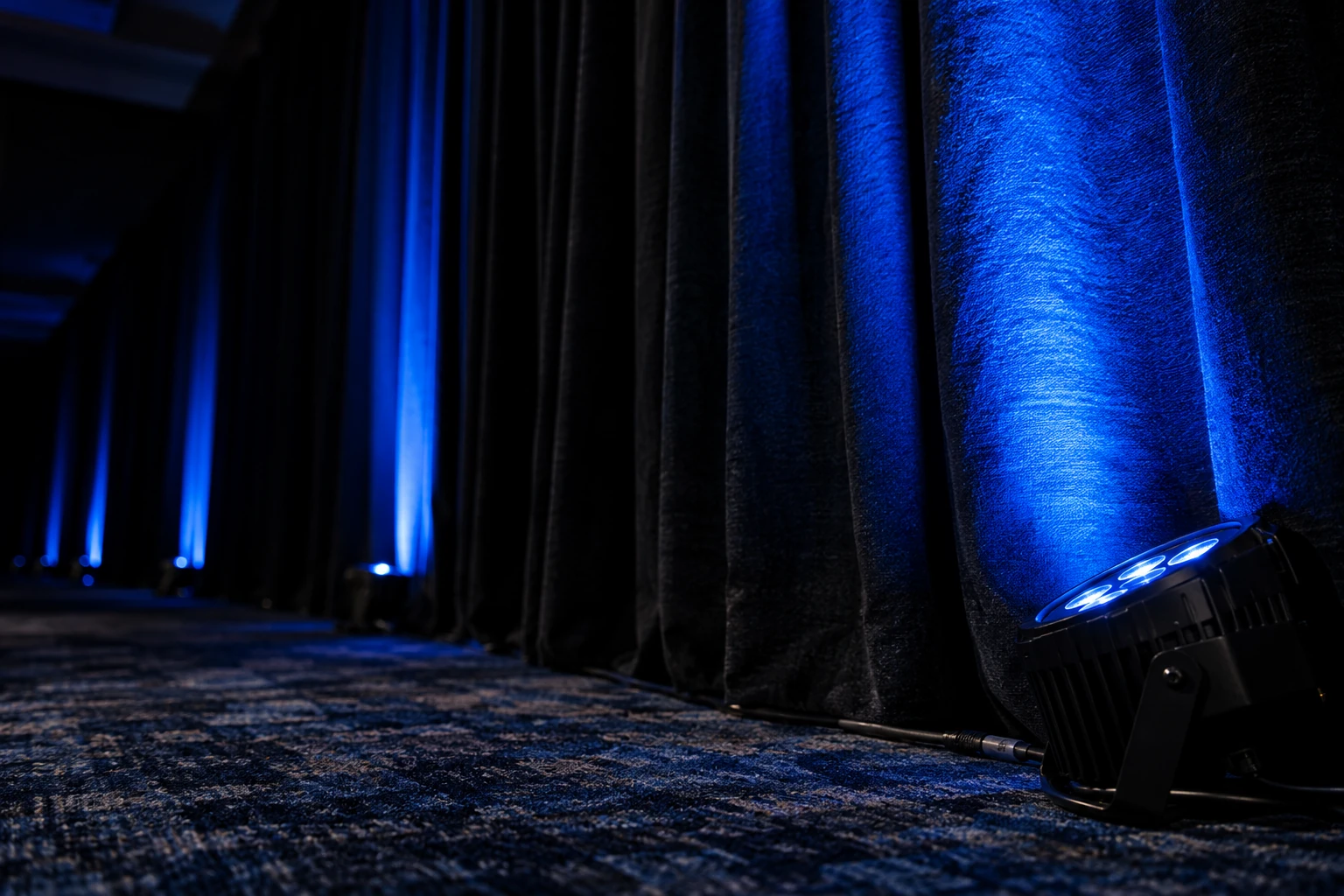 Blue uplighting on black conference drape
